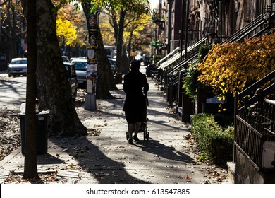 NEW-YORK - NOV 14: Woman Walking With Baby Cart In The Afternoon Hours On The Pavement In Brooklyn, New-York, USA On November 14, 2012.