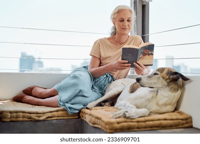 Next to dogs, books are my best friends. Shot of a mature woman reading a book on her balcony with her dog next to her at home. - Powered by Shutterstock