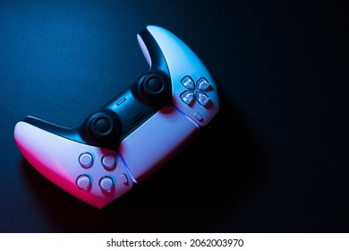 Next generation white game controller isolated on black background with colored lights illuminating it. Close-up. Selective focus.