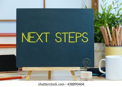  next steps -  text / message on the blackboard with the background of stationary on the office desk. the start-up  management concept
