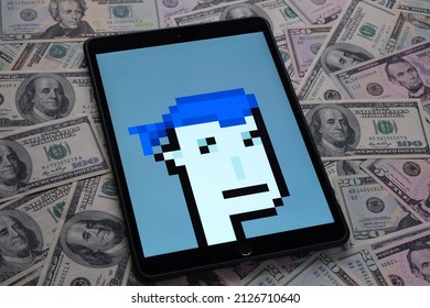 NFT Cryptopunk 5822 Form Larva Labs Seen On The Screen Of Ipad Placed On Dollar Bills. Digital Art Sold For Record Breaking 8000 ETH. Stafford, United Kingdom, February 13, 2021.