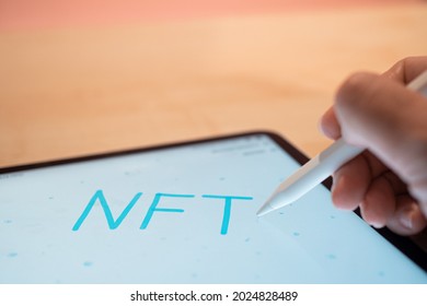 NFT Non-interchangeable token creation of crypto art, concept. NFT inscription on the tablet screen, hands write with a stylus in a graphic editor, digital art concept