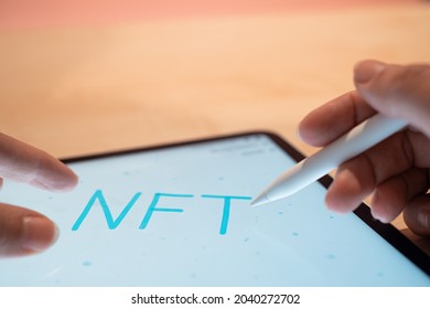NFT Non-interchangeable token creation of crypto art, concept. NFT inscription on the tablet screen, hands write with a stylus in a graphic editor, digital art concept