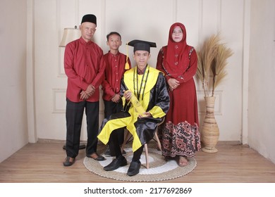 Nganjuk - East Java - Indonesia, 24 December 2021 Asian Boy In Graduation Gown. Take A Photo With The Family. Mom, Dad And Sister