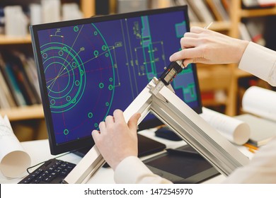 Ngineer Working On Cad Scheme Using Computer Tools. Engineer Measures A Mechanical Part With A Caliper.