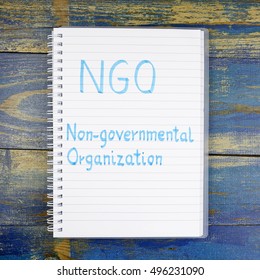 NGO- Non-Governmental Organization written in notebook on wooden background - Shutterstock ID 496231090