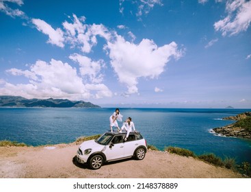 Nha Trang City, Viet Nam - May 2021: A Rich Asian Couple Sitting On The Roof Of A White Car On The Pass, Behind Is The Natural Scenery Of The Sea And The Sky. Happy Vacation.