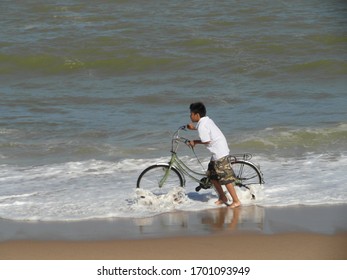 Nha Trang , Khanh Hoa / Vietnam - December 15 2012: Kid Pushing Bike In Beach Waves And Sand Right On The Beach 