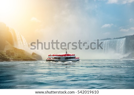 Niagara Falls boat tours attraction. Tourist people sailing on the travel boat close to the Niagara Horseshoe Fall at sunny hot summer day.