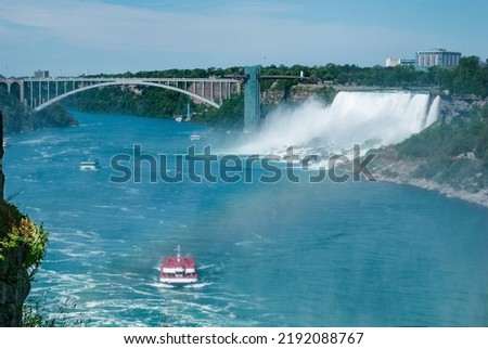 Niagara falls and Niagara river in Canada, Ontario. Three tourist boats sail on the Niagara river. In the background is a bridge between the Canadian and American border.