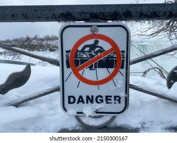 Niagra, Ontario- Feb 22, 2022: Do Not Climb Over The Fence Sign In Freezing Snow Winter With Niagra Falls As A Background.