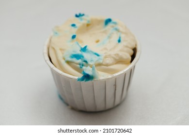 A Nibbled Or Spoiled Cream Cake In A Cardboard Basket On A White Table. The Concept Of Baking And Confectionery.