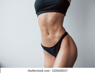 Nice abs. Particle view of hot slim body type of girl that stands in the room.