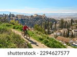 nice active senior woman cycling with her electric mountain bike in Granada below the world heritage site of Alhambra, Granada, Andalusia,  Spain,