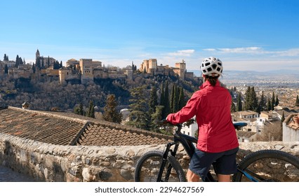 nice active senior woman cycling with her electric mountain bike in Granada below the world heritage site of Alhambra, Granada, Andalusia,  Spain, - Powered by Shutterstock