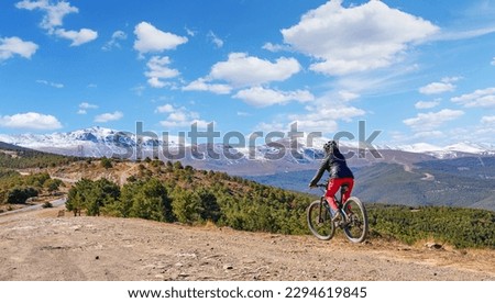 nice, active senior woman cycling with her electric mountain bike below the snow covered mountains of the Spanish Sierra Nevada, near Granada, Anslusia, Spain