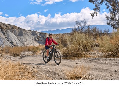 nice, active senior woman with her electric mountain bike on a trail tour in the desert of Tabernas near Almeria, Andlusia, Spain - Powered by Shutterstock