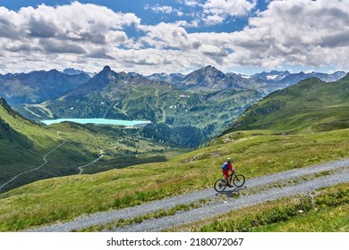 nice active senior woman riding her electric mountain bike in the silvretta mountain range above barrier lake Kopssee,near Gaschurn, Tyrol, Austria