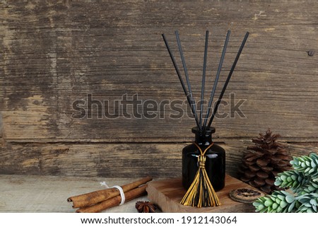 nice aromatic scented reed diffuser air freshener bottle on wooden table with pine cone and background of old vintage wooden texture wall of living room to creat realx ambient in cottage for christmas