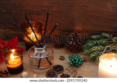 nice aromatic scented reed diffuser air freshener bottle on wooden table with pine cone and background of old vintage wooden texture wall of living room to creat realx ambient in cottage for christmas