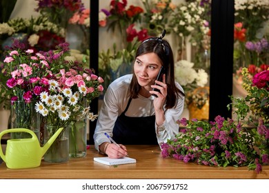 nice attractive flower shop owner talking on phone with client. Small business. confident professional florist taking notes, listen to orders of customers, going to make special bouquet - Powered by Shutterstock