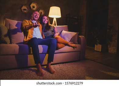 Nice Attractive Lovely Tender Glad Cheerful Cheery Couple Girl Sitting On Divan Watching Funny Film Having Fun Spending Day Weekend At Night Dark Home House Apartment Indoors