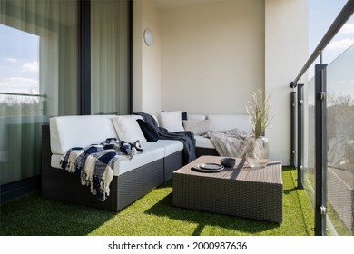 Schöner Balkon mit RattanEcksofa und Couchtisch und synthetischem Gras auf dem Boden