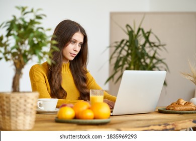 Nice Beautiful Female With Blonde Long Hair Working On Laptop Sitting At Home. Online Shoping, Alternative Office Freelance, Gig Economy, Digital Nomad