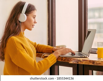 Nice Beautiful Female With Blonde Long Hair Working On Laptop Sitting At Home. Online Shoping, Alternative Office Freelance, Gig Economy, Digital Nomad