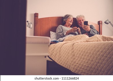 Nice Beautiful Models Couple Of Adult Senior 70 Years Old Having Fun And Enjoy In Bed At Home In Bedroom. Morning Lazy Wake Up With No Rush Checking Emails And Contents On The Smartphone 