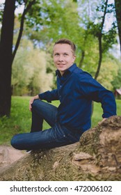 Nice boy seating on tree trunk. 