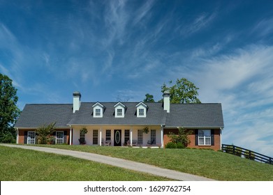 A Nice Brick Ranch House On A Grassy Hill With Blue Sky