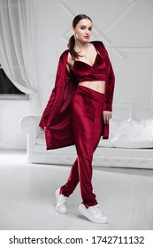 Nice Brunette Dressed In A Burgundy Velour Suit Posing In The Studio