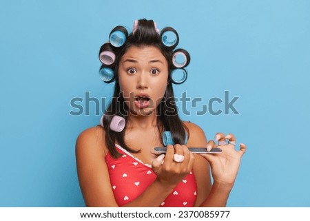 Nice brunette girl with big hair wavers doing nails with emery board, wearing red home top, good mood concept, copy space