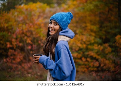 Nice brunette happy woman in knit hat drinking tea while strolling in autumn forest - Powered by Shutterstock