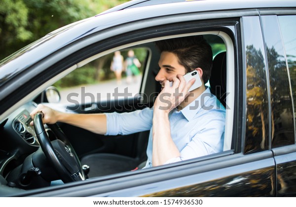 Nice\
business talk. Handsome young businessman talking on his smart\
phone and smiling while sitting on the front\
seat