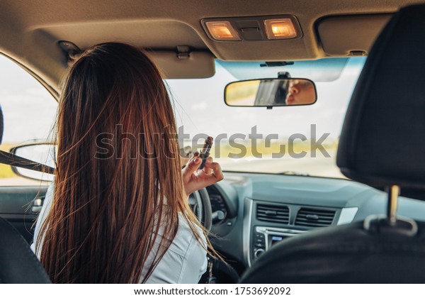 Nice\
business woman driving a car and painting her lips.\
