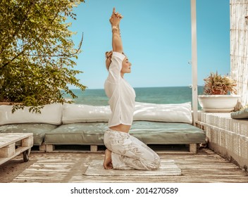 Nice Calm Female Doing Yoga Exercises On The Terrace Of Beach House. Meditating On The Beach. Zen Balance. Peaceful Summer Vacation.