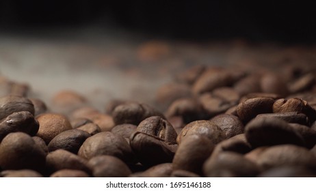 Nice and cinematic footage of roasted coffee beans. Camera slowly fly above coffee beans with smoke with black background.