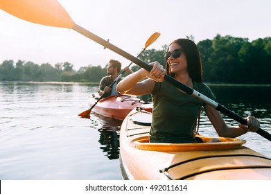 Buen día para el kayak. Hermosa pareja joven kayak en el lago juntos y sonriendo