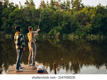 Nice day out. Unusual romantic date in countryside. Young beautiful couple standing on pier and fishing. Beauty of nature. Summer weekends. Fresh air breathing. Concept of leisure time activity, ad