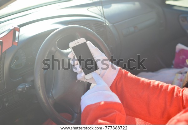 Nice, France - 06 December 2017: Closeup on\
driving car Santa Claus using Apple Iphone 8 smartphone online\
mockup background. Joyful tradition celebration, busy season\
delivering time, outdoors\
window