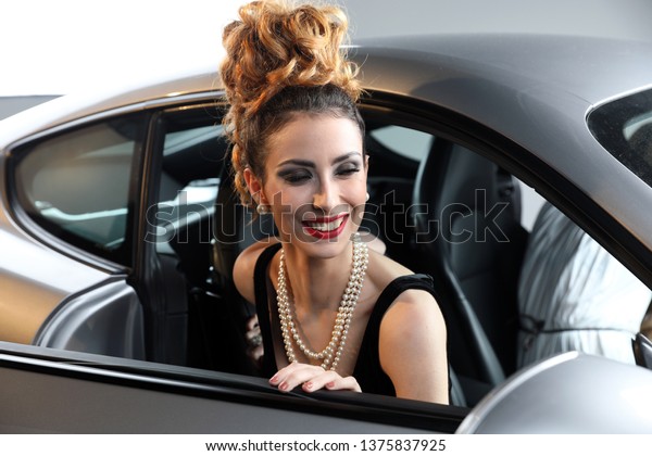 Nice, France\
- April 12, 2019: Smiling Fashion Model With A Pearl Necklace\
Posing In A Sports Car, Beautiful Woman Inside Porsche Cayman In\
The Studio, Portrait Close Up\
View