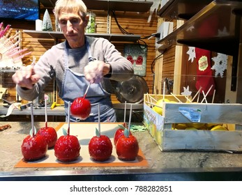 NICE, FRANCE - DECEMBER 02, 2017 : A Man Is Putting Red Apples In Sugar Icing Toffee For Sale At Candy Food Stall In Christmas Market. Selective Focus. Winter Season.