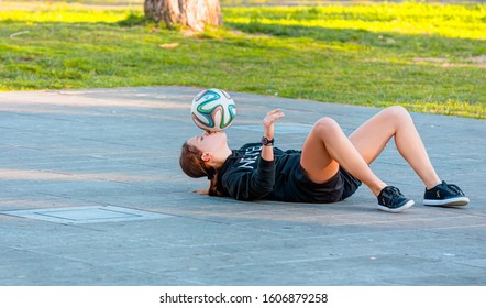 NICE, FRANCE - DECEMBER 30 2019: Young Girl Soccer Player On The Street - A Girl Plays With The Soccer Ball Alone On A Street Soccer