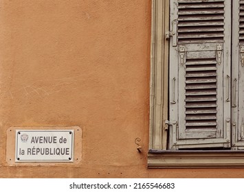 NICE, FRANCE - MAY 25, 2018:  Shuttered Window On Yellow Apartment Building With Street Sign For Venue De La  Republique