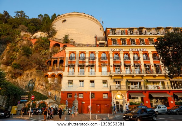 Nice, France - September 20, 2018: The\
evening sunset light illuminates the facade of the famous hotel.\
You can also see the stairs leading to castle\
hill.