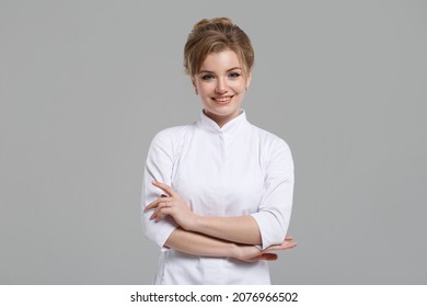 Nice girl doctor in a white coat isolated on a gray background.