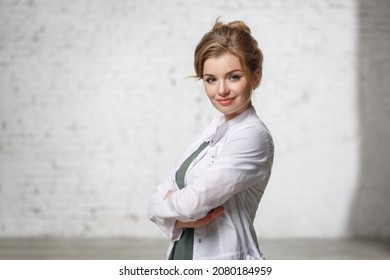 Nice girl doctor in a white coat on a light background.