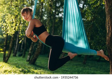 Nice girl doing fly yoga in park outdoors . Happily looking at the camera - Powered by Shutterstock